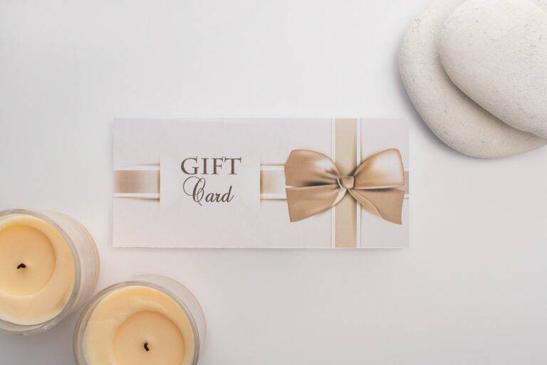 Top view of gift card near candles and zen stones on white background