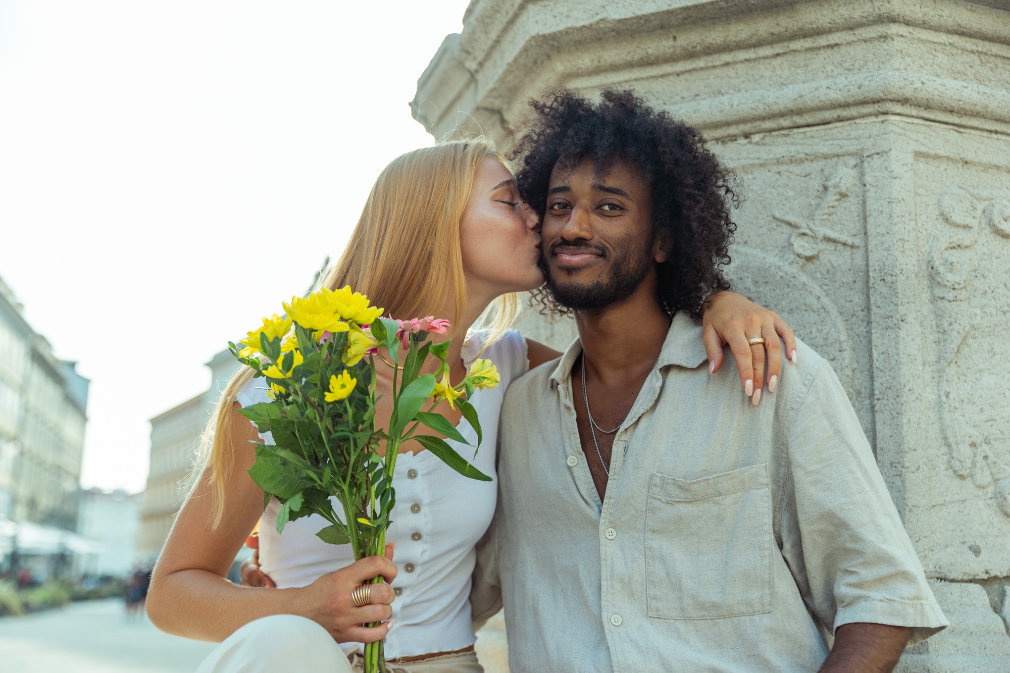 Boyfriend receives a kiss from his girlfriend after giving her a bouquet of flowers, mixed couple