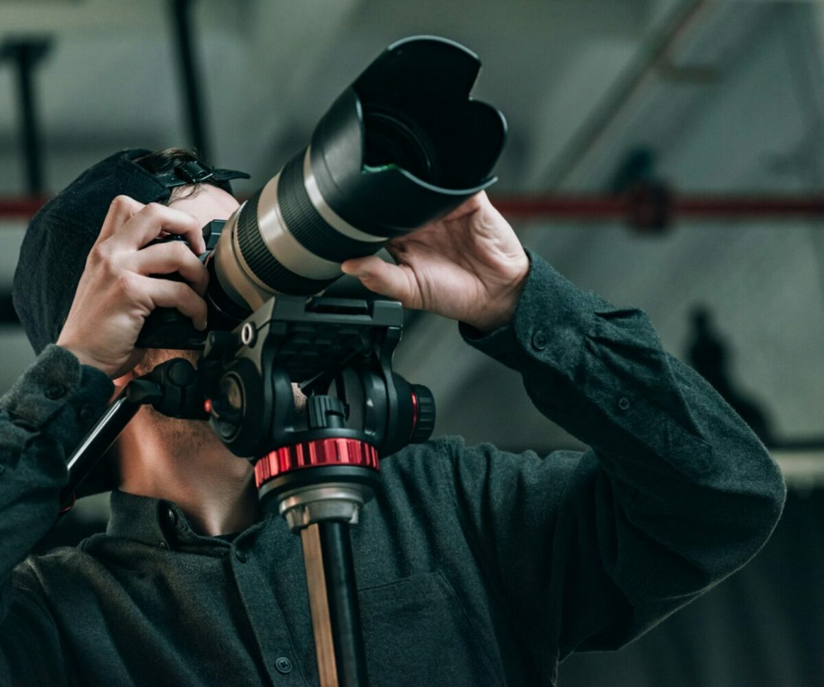 Low angle view of videographer with camera on tripod in photo studio